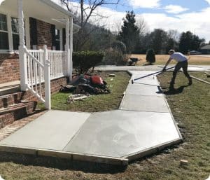Freshly poured concrete walkway with forms, and a worker finishing the surface in Richmond VA