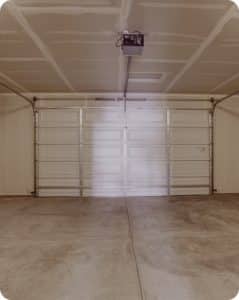 Plain gray garage floor with control joints and attached white garage door in Richmond VA