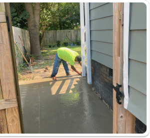 Freshly poured concrete patio being finished next to a house foundation and fence in Richmond VA