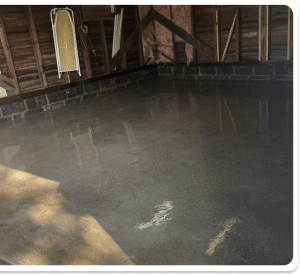 Smooth concrete garage floor with a dark brick wall border and rough-finished wood walls in Richmond VA
