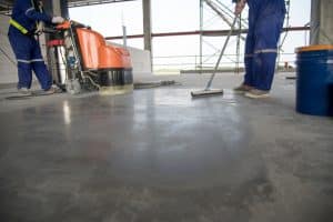 Gray polished concrete floor being cleaned by workers in an industrial setting in Richmond VA