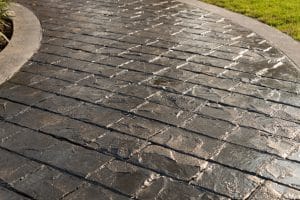 Dark gray stamped walkway with a textured border, next to lawn and plants in Richmond VA