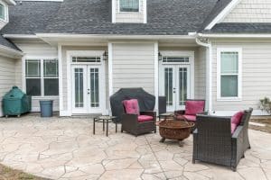 Stamped concrete patio with flagstone pattern, light color, by house with outdoor furniture in Richmond VA