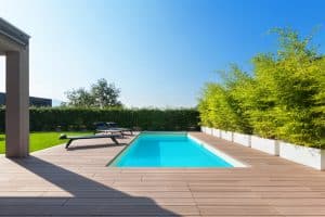 Wooden deck surrounding a rectangular pool with lounge chairs and bamboo plants in Richmond VA