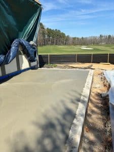 Wet, freshly poured concrete slab next to forms, with a distant golf course in Richmond VA