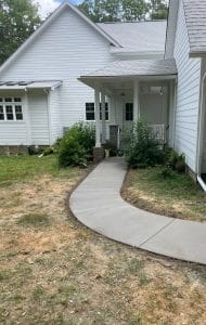 Broom-finished concrete walkway with expansion joints leading to a white house's front porch in Ashland VA