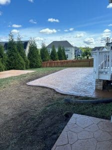 Stamped concrete patio with brown flagstone pattern and dark border next to a deck in Goochland VA