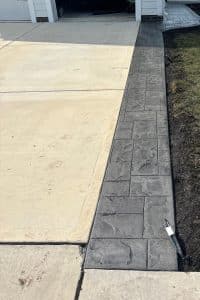 Stamped concrete walkway with dark ashlar pattern bordering a lighter concrete driveway in New Kent VA