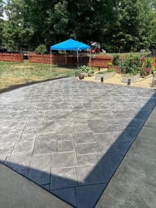Dark gray stamped concrete patio with ashlar slate pattern bordering an existing concrete slab in Chester VA