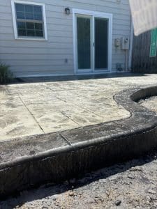 Stamped concrete patio with ashlar pattern and dark curved border next to a house in Ashland VA