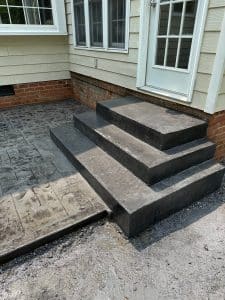 Dark gray concrete steps leading to a stamped patio with brick-like pattern in Short Pump VA