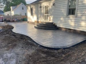 Stamped concrete patio with ashlar slate pattern, dark border, and matching steps beside house in Short Pump VA