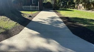 Broom-finished concrete walkway with expansion joints and fresh dirt landscaping on sides in Chesterfield VA