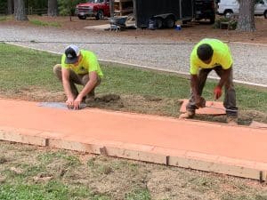 Unfinished colored concrete walkway being worked on by two contractors in Chesterfield VA