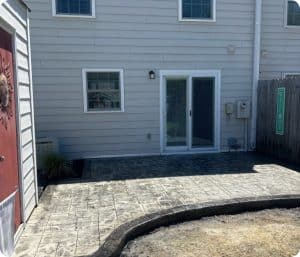 Stamped concrete patio with cobblestone pattern and curved border next to shed and house in Richmond VA