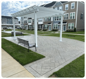 Gray stamped concrete patio with ashlar slate pattern and darker border under a white pergola in Richmond VA