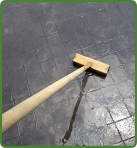 Wet, dark gray stamped concrete patio with square tile pattern being scrubbed in Richmond VA