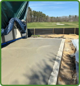 Rough-finished gray concrete slab partially covered by tarp, with golf course backdrop in Richmond VA