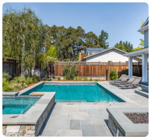 Gray flagstone pool deck with surrounding stone planters and fire pit in Richmond VA