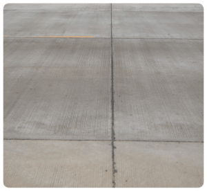 Broom-finished concrete surface with black expansion joints and faint yellow line marking in Richmond VA