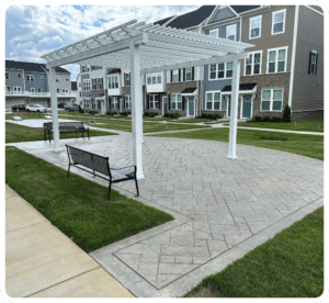 Stamped concrete patio with ashlar slate pattern and decorative border under white pergola in Richmond VA