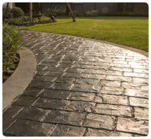 Stamped dark gray concrete walkway with irregular brick pattern and smooth border, next to lawn in Richmond VA