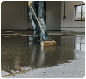 Worker applying liquid coating with roller on a concrete garage floor in Richmond VA